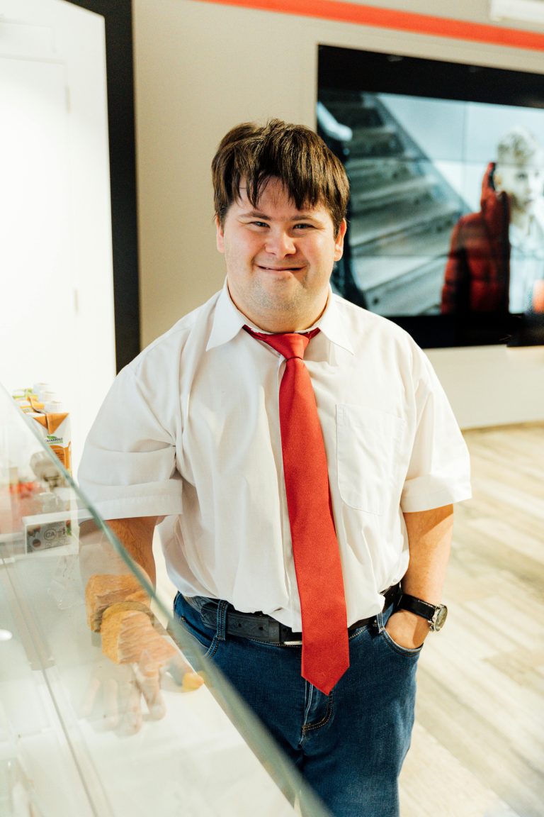 A confident man with Down Syndrome smiling in a modern office environment.